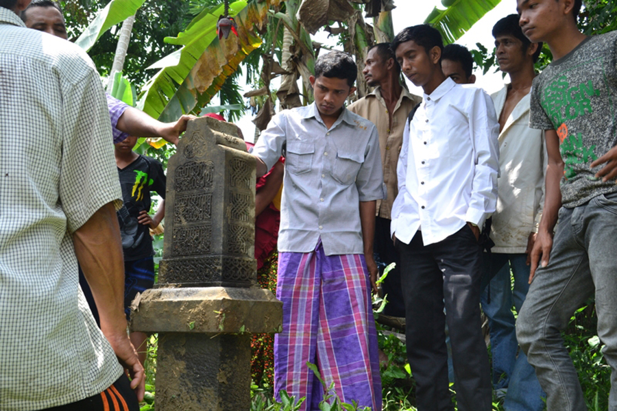 Warga melihat salah satu nisan makam yang ditemukan dalam aliran Krueng Pase | Foto: Cisah